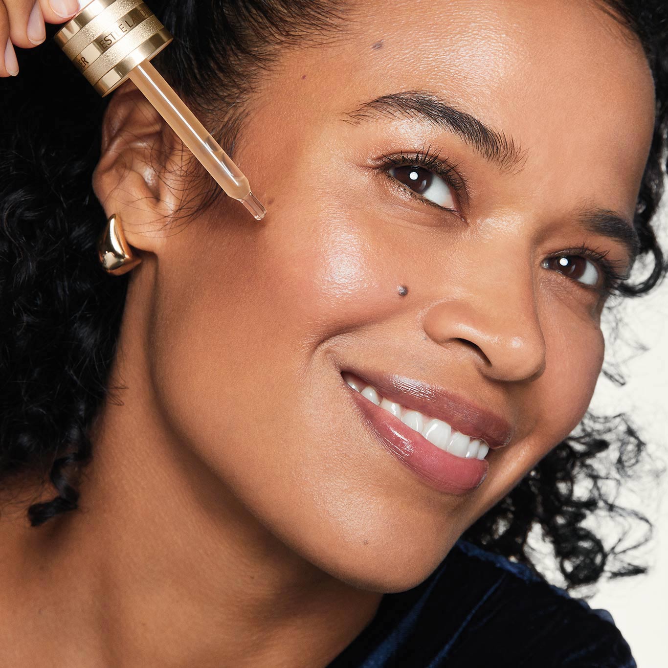 Smiling woman applying Advanced Night Repair Serum with the pipette