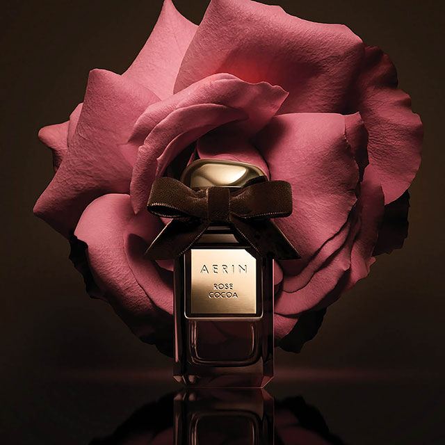 New AERIN Rose Cocoa fragrance on a dark brown background